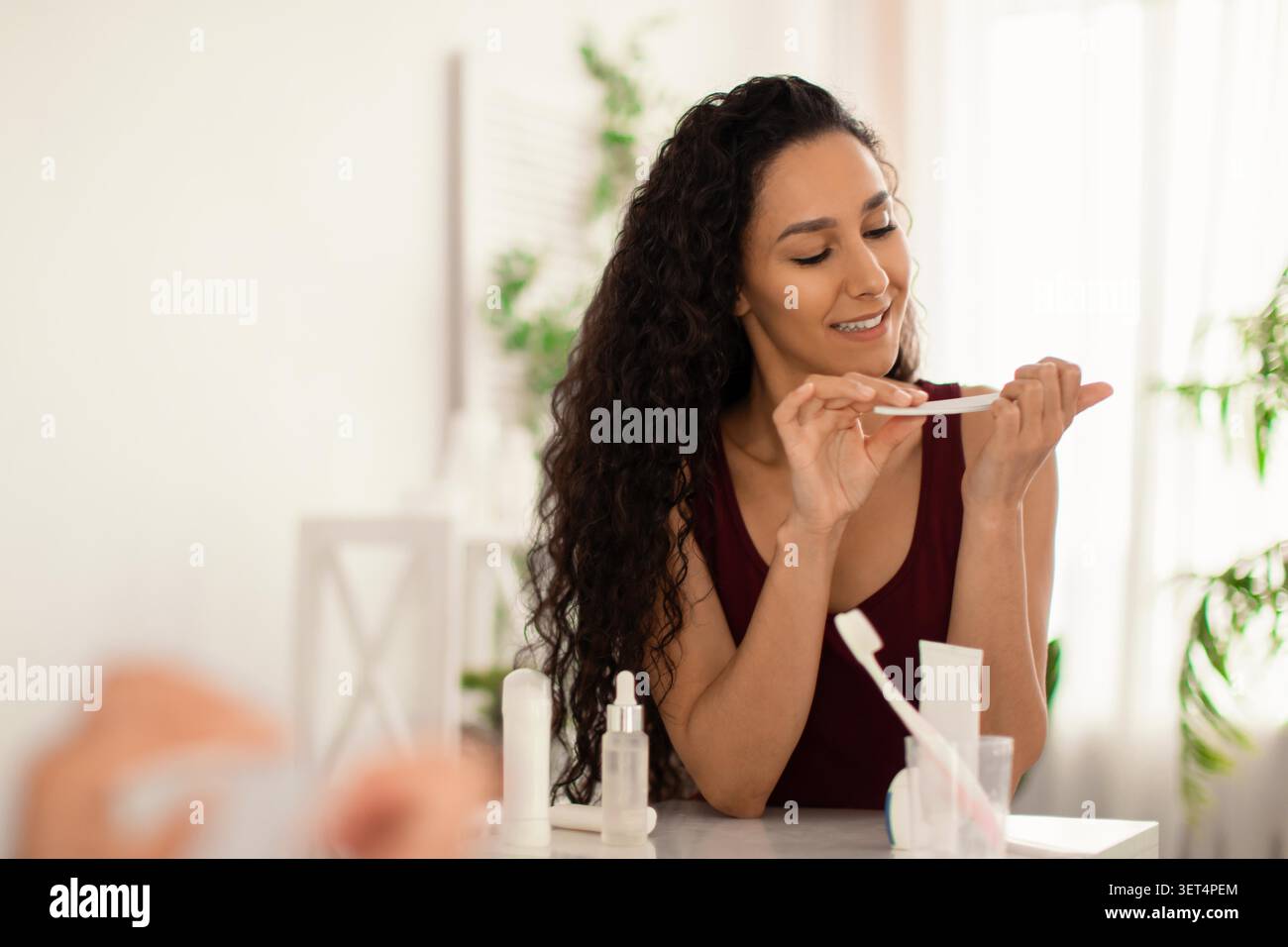 Happy Young Woman analizza il prodotto per la cura della pelle a casa, concetto di auto-cura Foto Stock