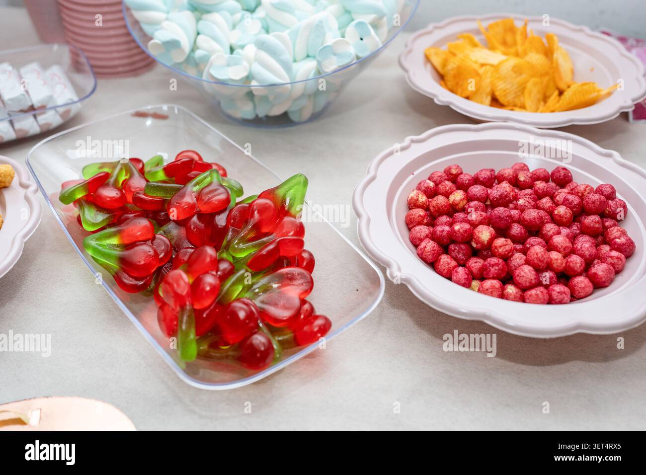 Caramelle, marshmallow e spuntini serviti al tavolo della festa di compleanno. Una scena alimentare colorata legata a discussioni sui divieti artificiali di coloranti, sulla consapevolezza degli ingredienti e sulle tendenze dei consumatori di etichette pulite. Foto Stock