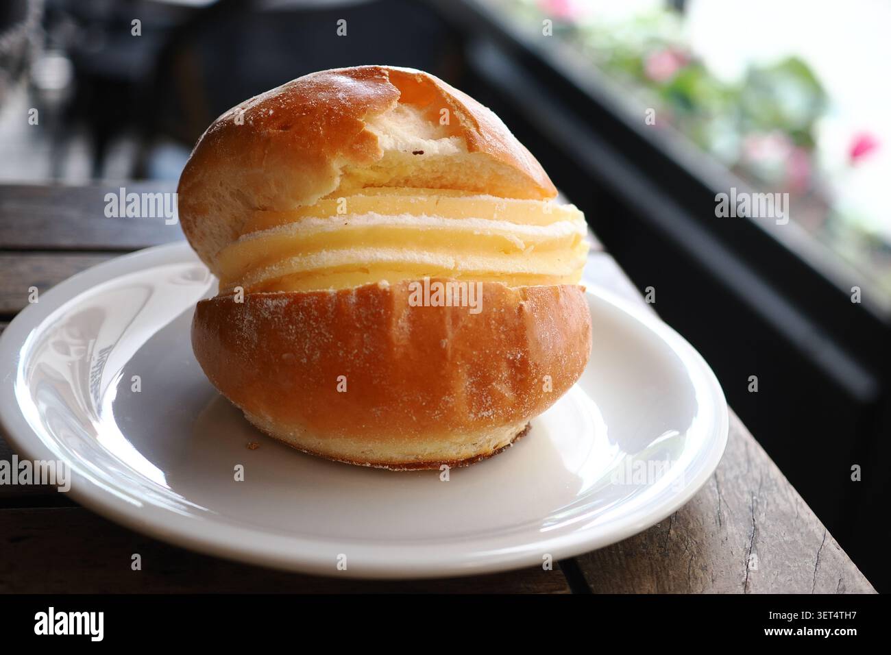 Panino fresco ripieno di panna su un piatto bianco Foto Stock