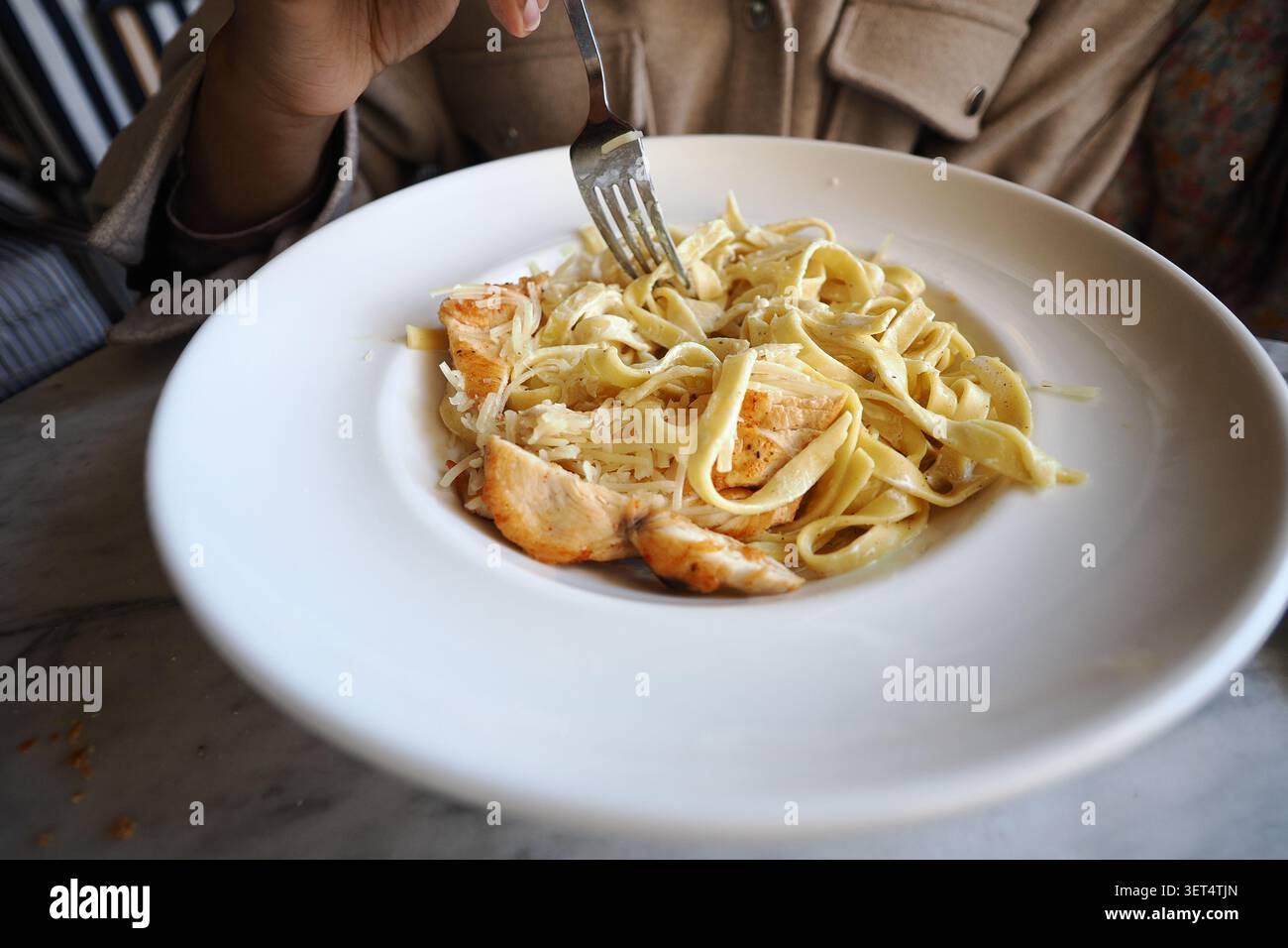 Gusta un piatto di pasta con pollo in un ristorante Foto Stock