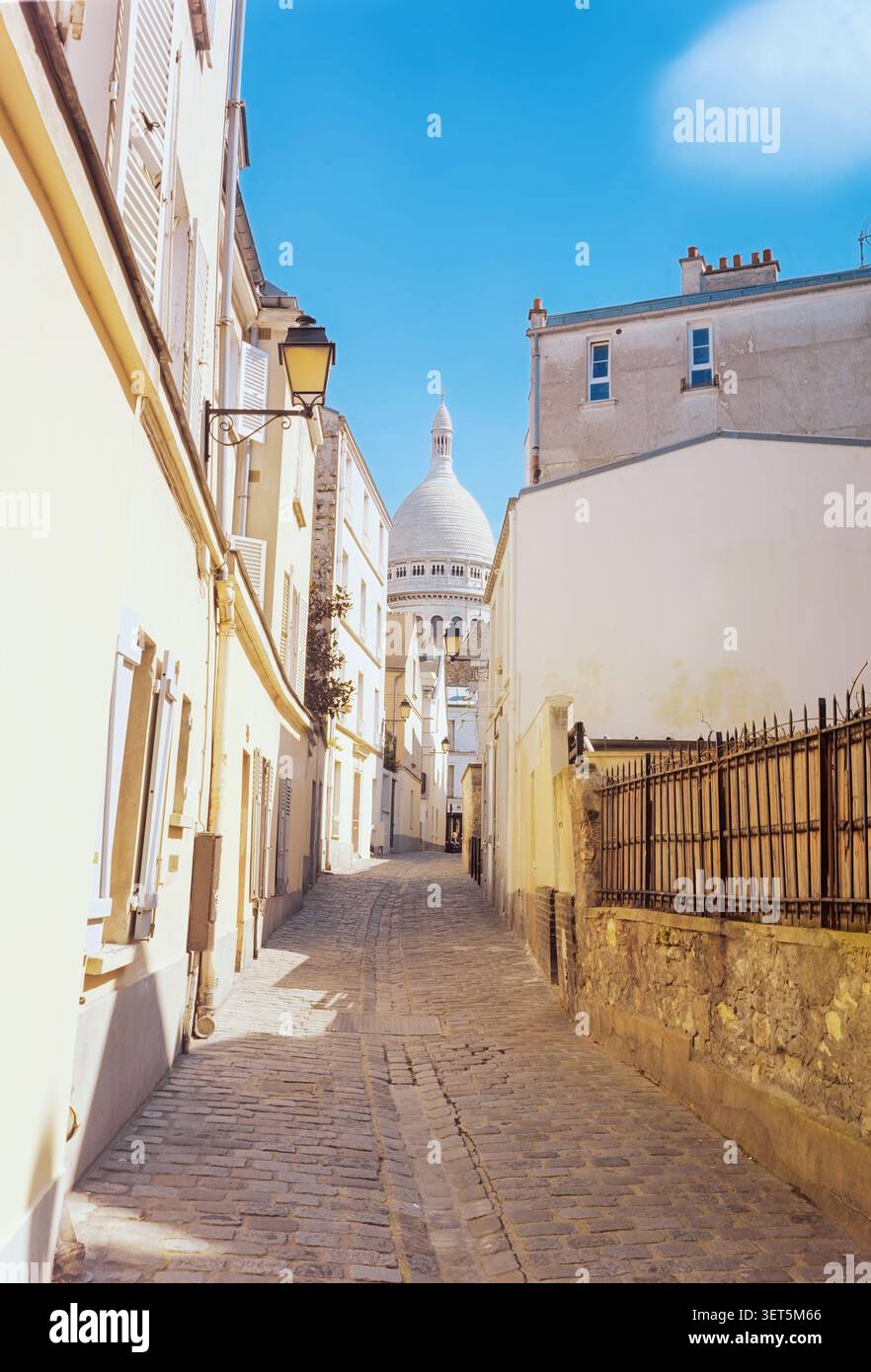 Un pittoresco vicolo parigino, incorniciato da edifici affascinanti e che conduce verso la maestosa cupola della Basilica del Sacro cuore Foto Stock