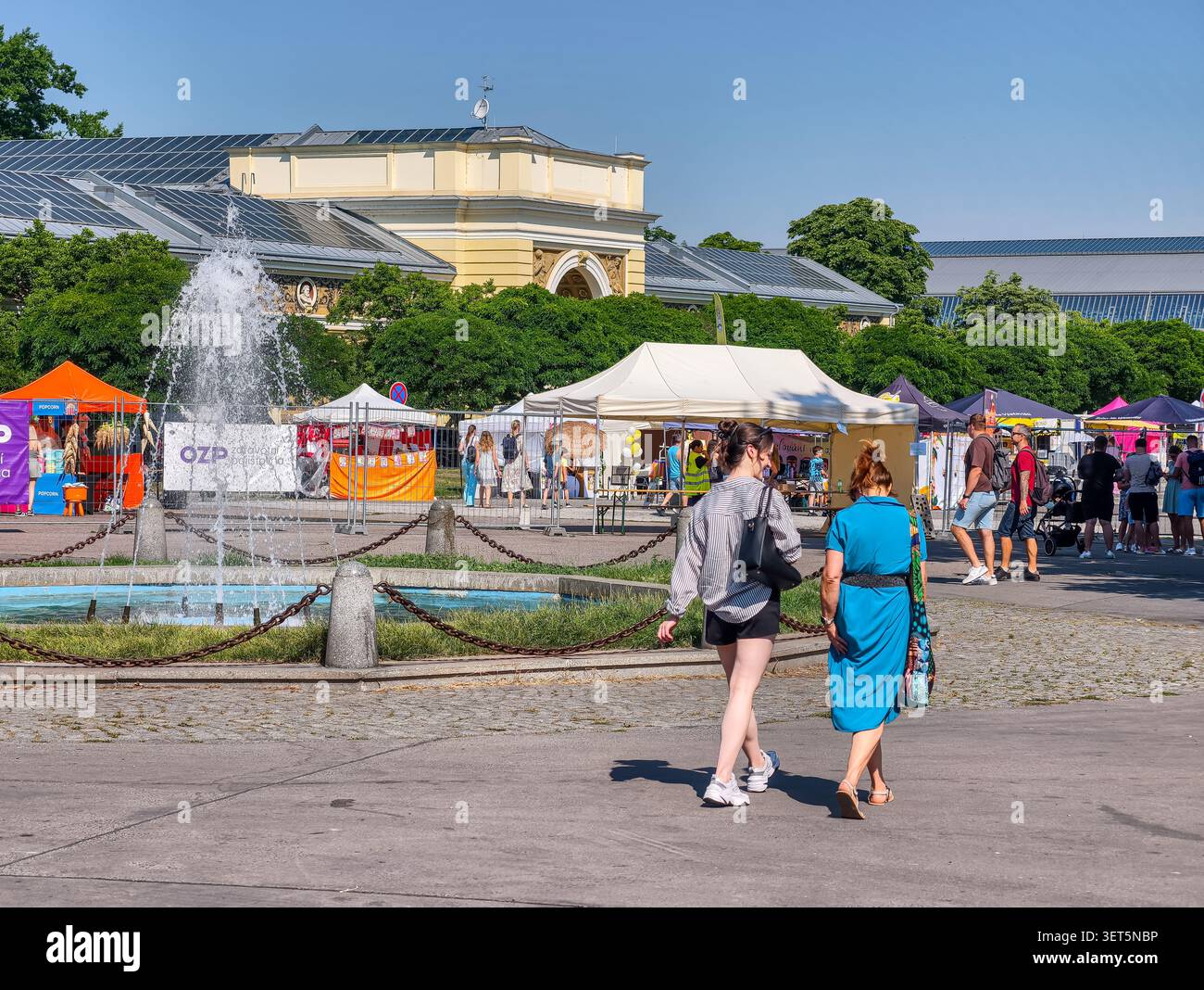 Praga, Repubblica Ceca - 21 giugno 2026: I visitatori possono godersi una giornata di sole alla mostra di Praga, passeggiando attraverso un'affollata area di mercato all'aperto vicino a una fontana Foto Stock