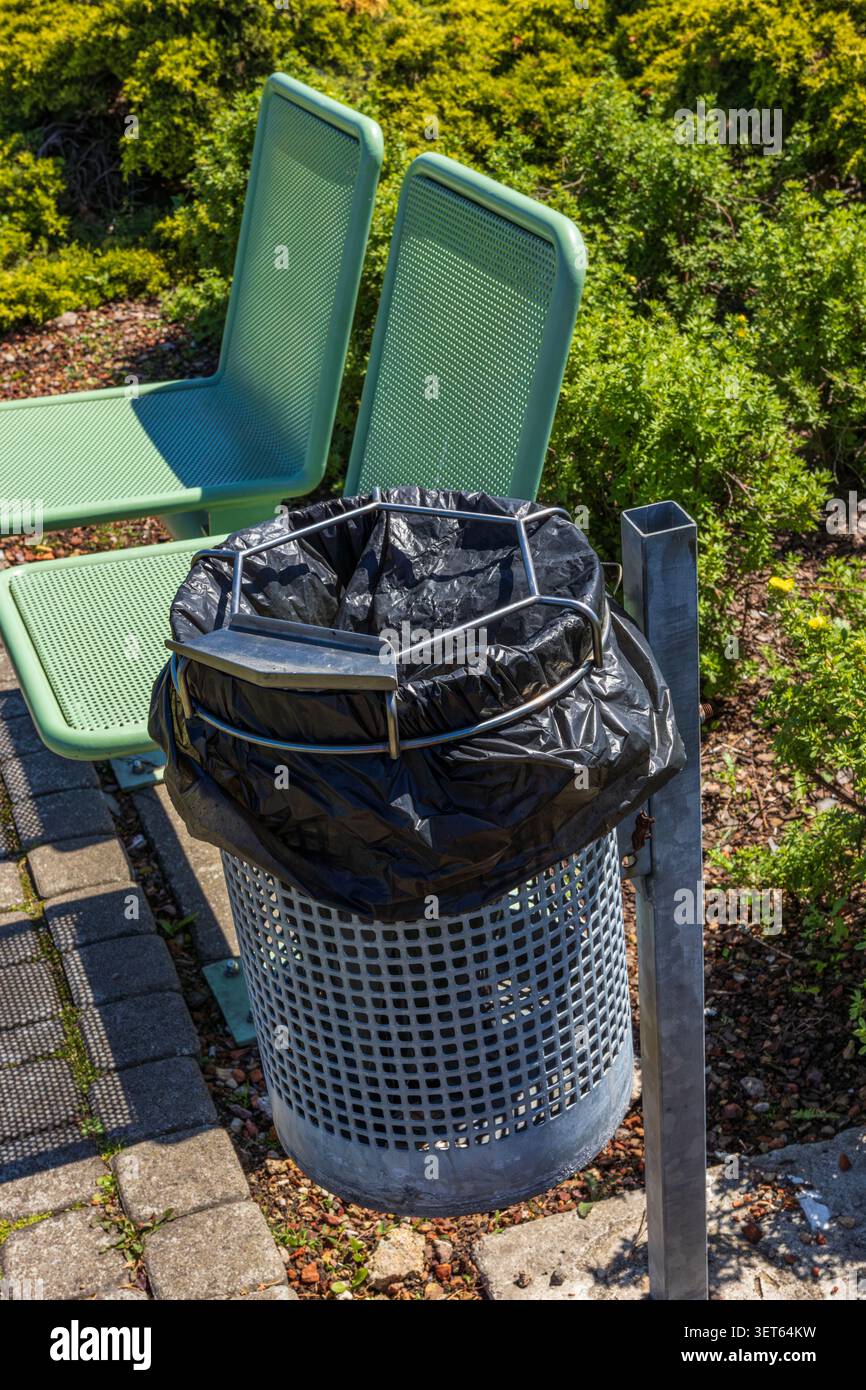Cestino pubblico e panca verde nel parco urbano paesaggistico Foto Stock