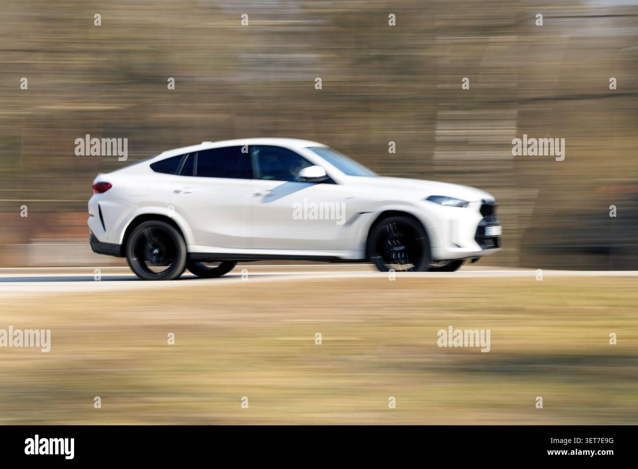 Immagine di sfocatura in movimento con vista laterale di un SUV bianco premium che corre in velocità lungo un'autostrada. Foto Stock