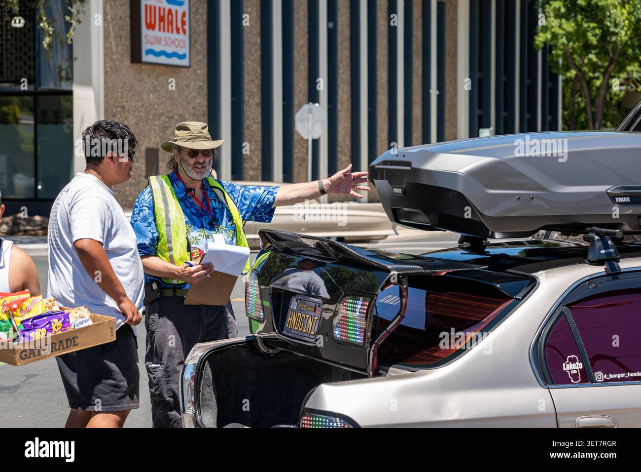 Un giudice che tiene un appunti parla con il proprietario di un'auto durante le valutazioni del veicolo alla Homecoming Broadway Cruise di Sacramento, California. Foto Stock
