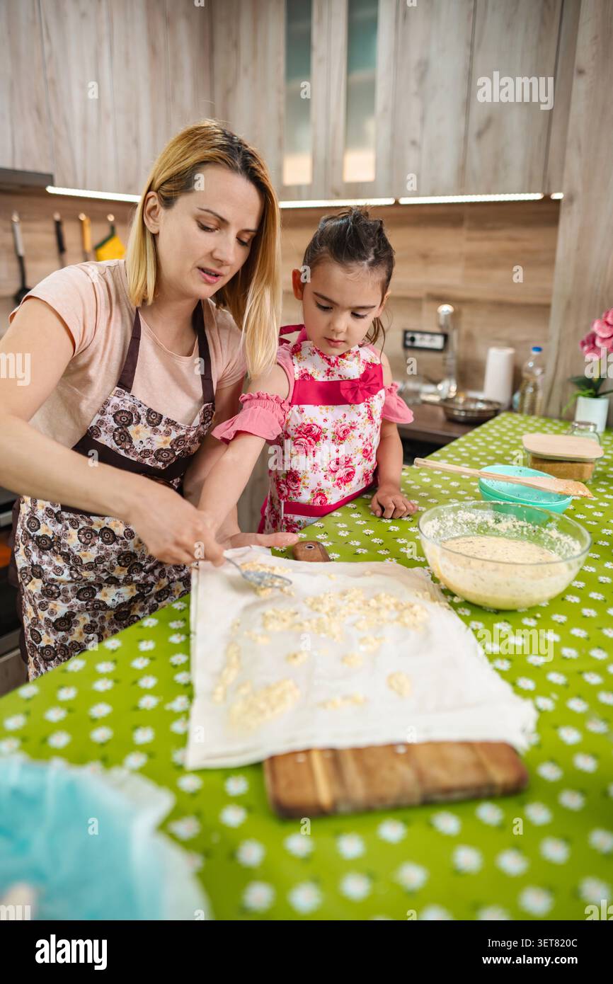 Madre e figlia cucinano insieme in un'accogliente cucina Foto Stock