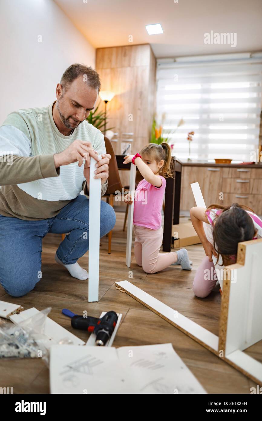 La famiglia si unisce a un divertente progetto fai-da-te in un accogliente soggiorno Foto Stock