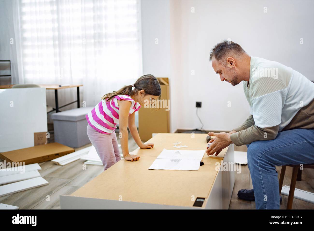 Padre e figlia lavorano insieme a un progetto di casa divertente Foto Stock