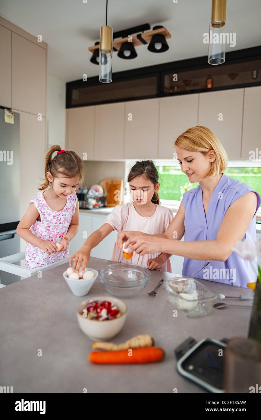 Un momento di cottura allegro con i bambini che preparano un dolce Foto Stock