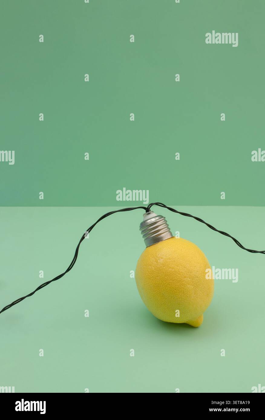 Immagine minimalista di un limone combinata con un portalampada su sfondo verde, simboleggia l'innovazione sostenibile, la tecnologia verde e. Foto Stock
