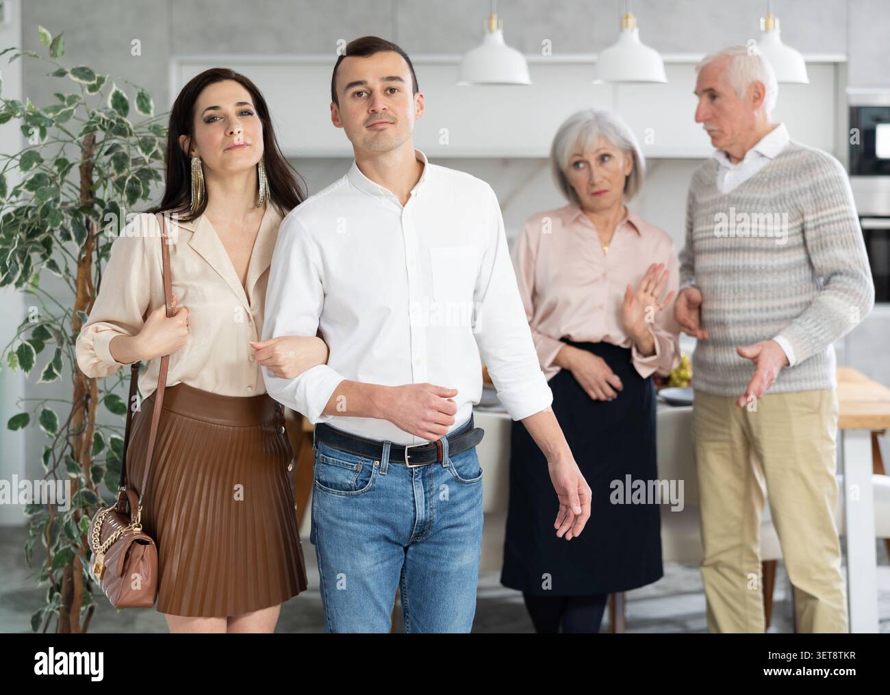 Coppia che se ne va con un uomo che fa gesto per fermare le dispute con i genitori Foto Stock