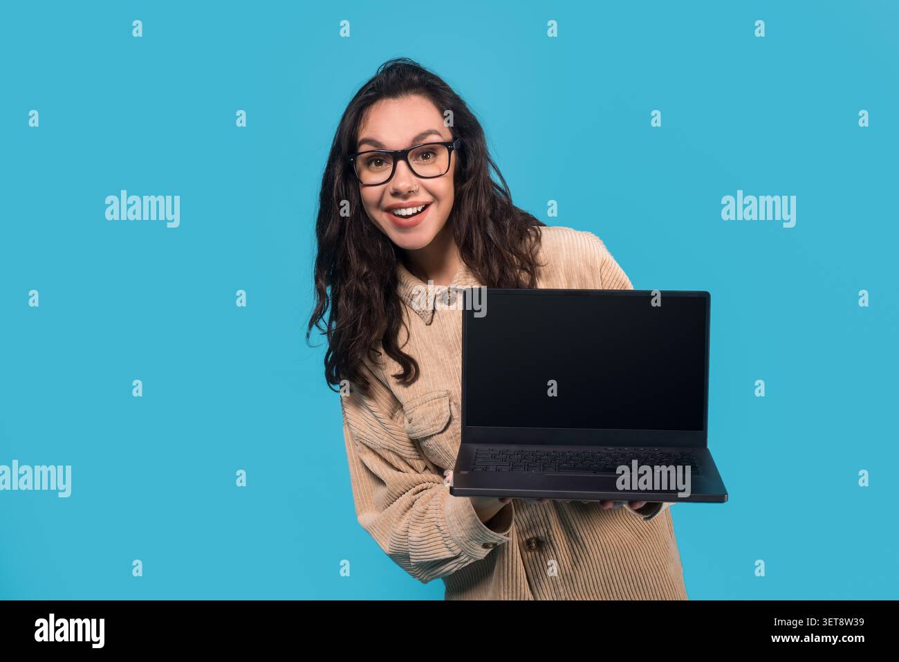 Giovane donna ispanica sorridente con laptop vuoto su sfondo blu, concetto tecnologico Foto Stock