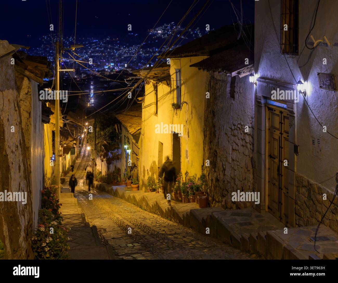 Strada notturna a Cusco, Perù, che si arrampica su una ripida pendenza, con turisti pedonali. Foto Stock
