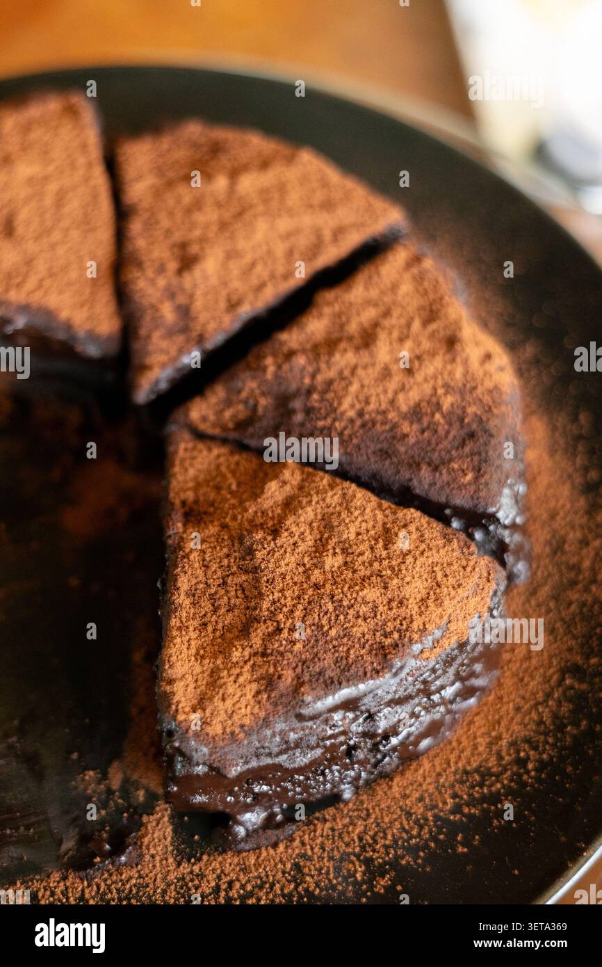 Torta al cioccolato dessert in polvere di cacao dolce fatto in casa, ricco e umido, deliziosa torta al cioccolato con polvere di cacao tagliata in pezzi Foto Stock