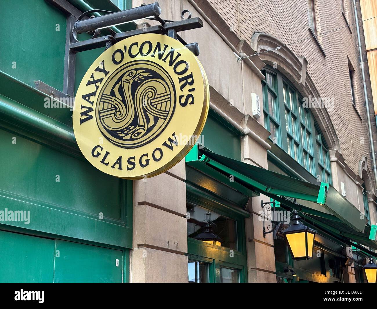 Segnaletica esterna per il pub Waxy o'Connor's di Glasgow, Scozia, con un cartello rotondo in oro e un design ispirato al concetto celtico. Foto Stock