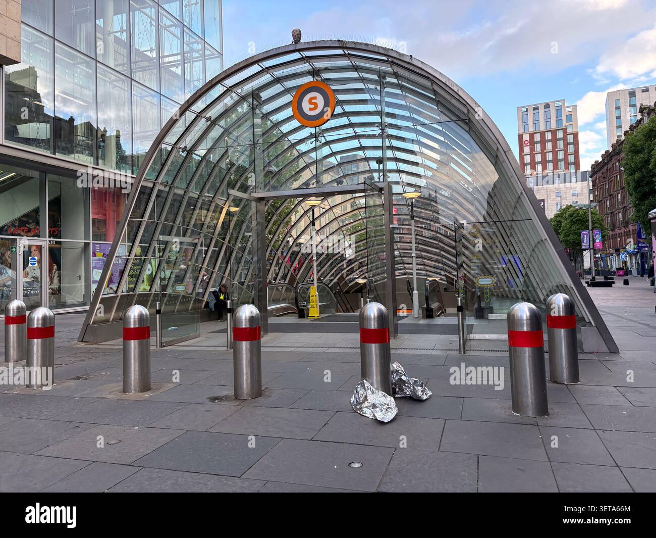 La moderna entrata in vetro ad arco della stazione della metropolitana di St. Enoch, Glasgow, Scozia, presenta un'importante insegna arancione con la lettera S. Foto Stock