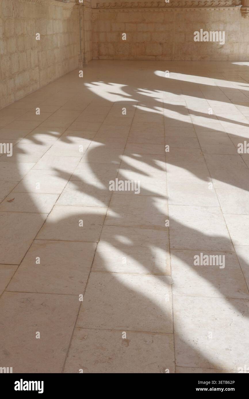 Motivi d'ombra dell'arco astratto su pavimento in pietra, Galleria del chiostro Mosteiro dos Jerónimos, Lisbona Foto Stock