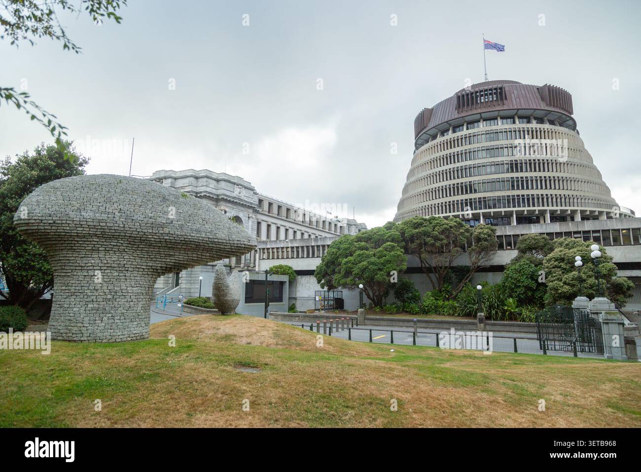Kaiwhakatere, The Navigator, una grande scultura in mattoni di pietra situata nel Bolger Park con gli edifici del Parlamento neozelandese Beehive. Foto Stock