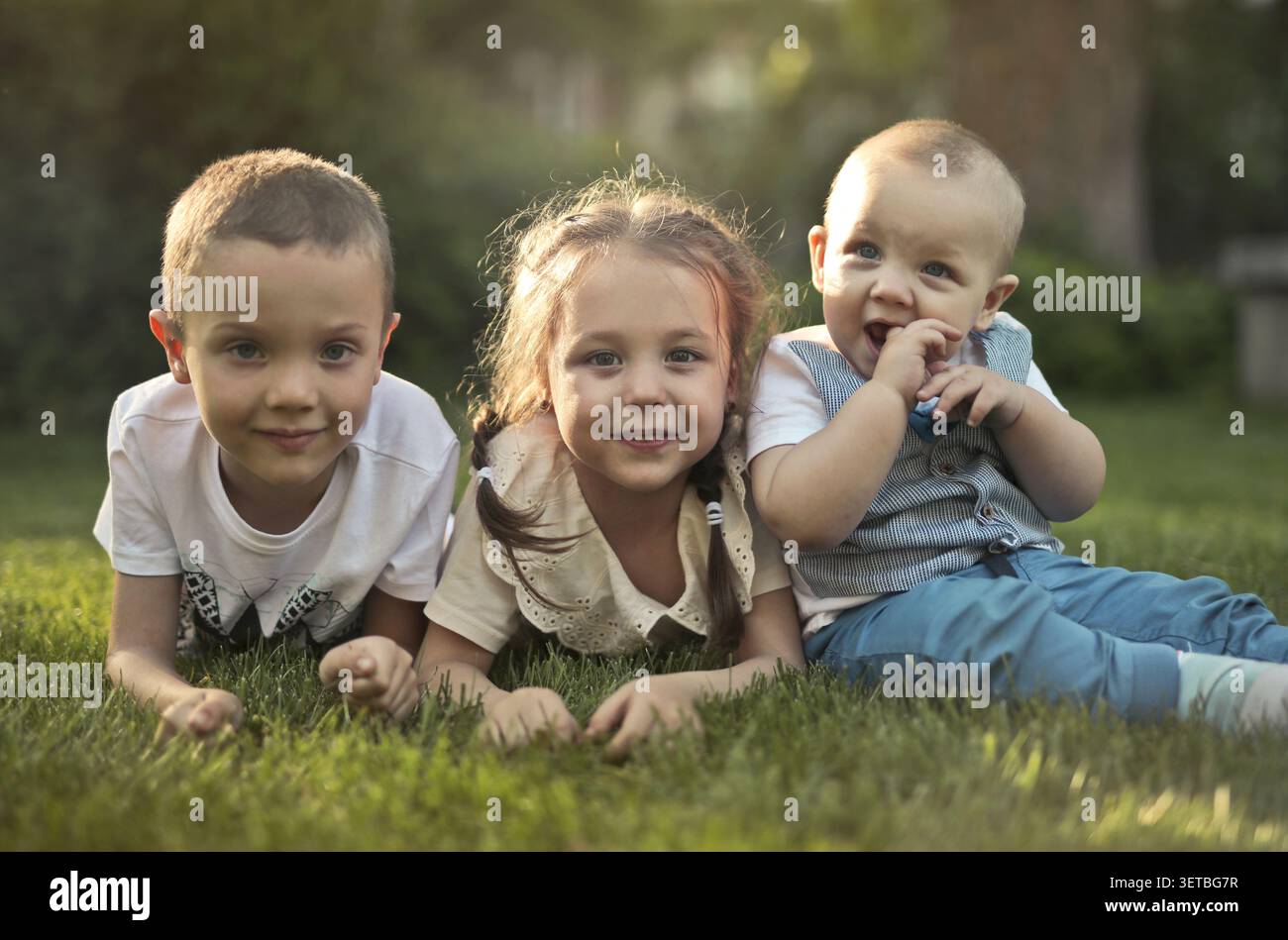 Tre bambini felici che si rilassano sull'erba Foto Stock