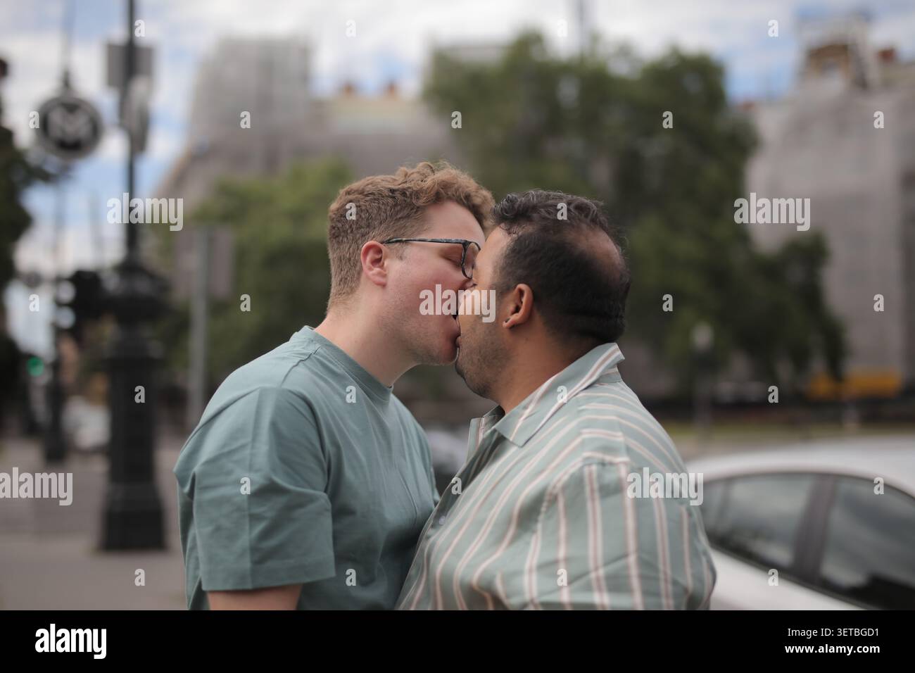 Una coppia gay che condivide un bacio romantico fuori Foto Stock