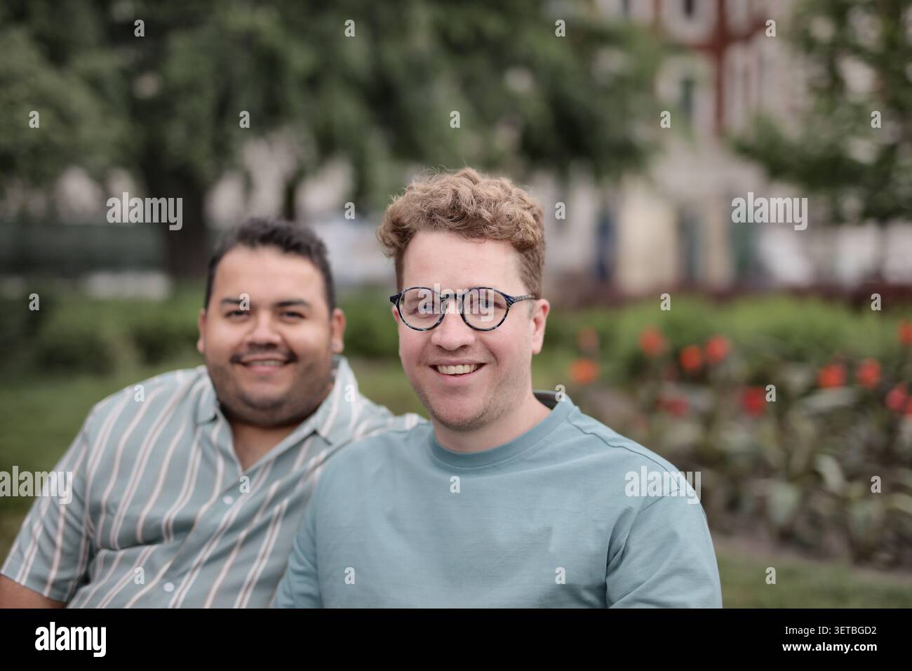 Due amici maschi felici seduti insieme in un parco Foto Stock