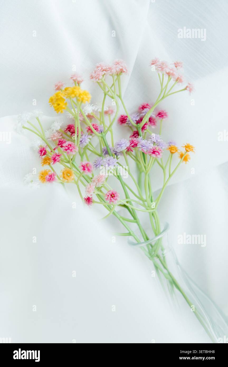 Una composizione delicata ed estetica caratterizzata da un bouquet di piccoli, vibranti e multicolori fiori artificiali di gypsophila Foto Stock