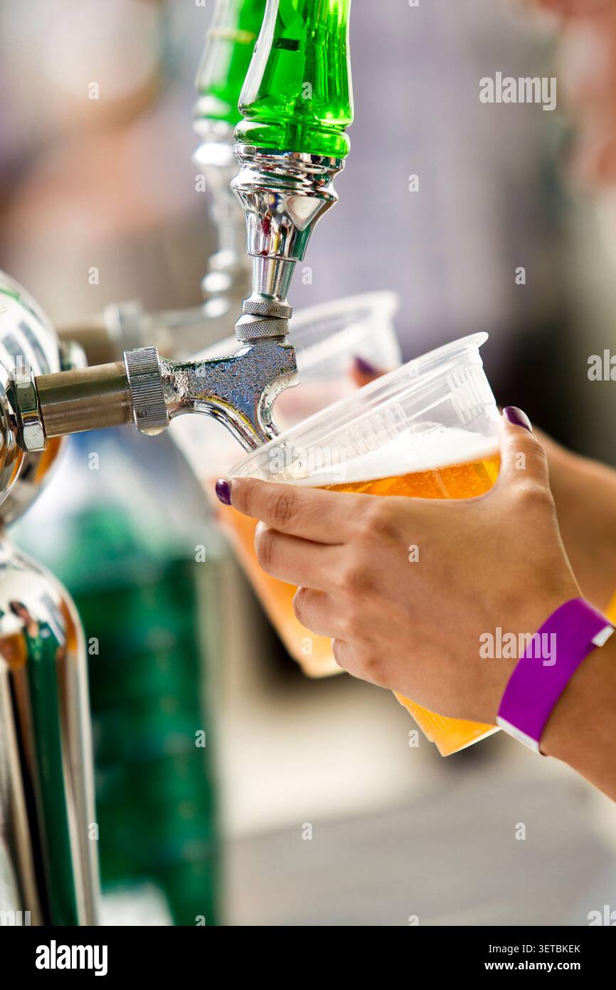 Primo piano di un barista che versa birra alla spina da un rubinetto in una plastica Foto Stock