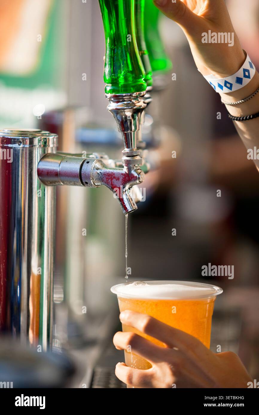 Primo piano di un barista che versa birra alla spina da un rubinetto in una plastica Foto Stock