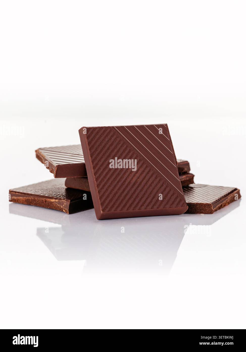 Sottili quadrati di cioccolato fondente impilati insieme Foto Stock