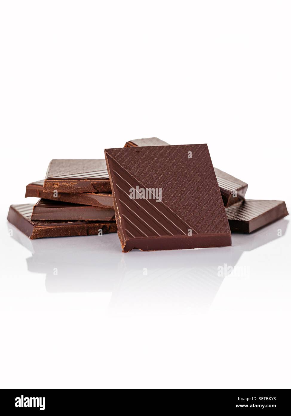Pezzi di cioccolato fondente impilati su uno sfondo bianco Foto Stock
