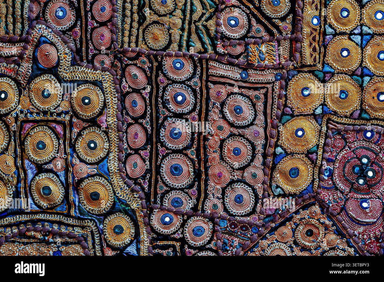Tappezzeria in mosaico indiano Rajasthani con texture ricamata a specchio. Primo piano del tradizionale tessuto patchwork indiano fatto a mano del Rajasthan con il colon Foto Stock