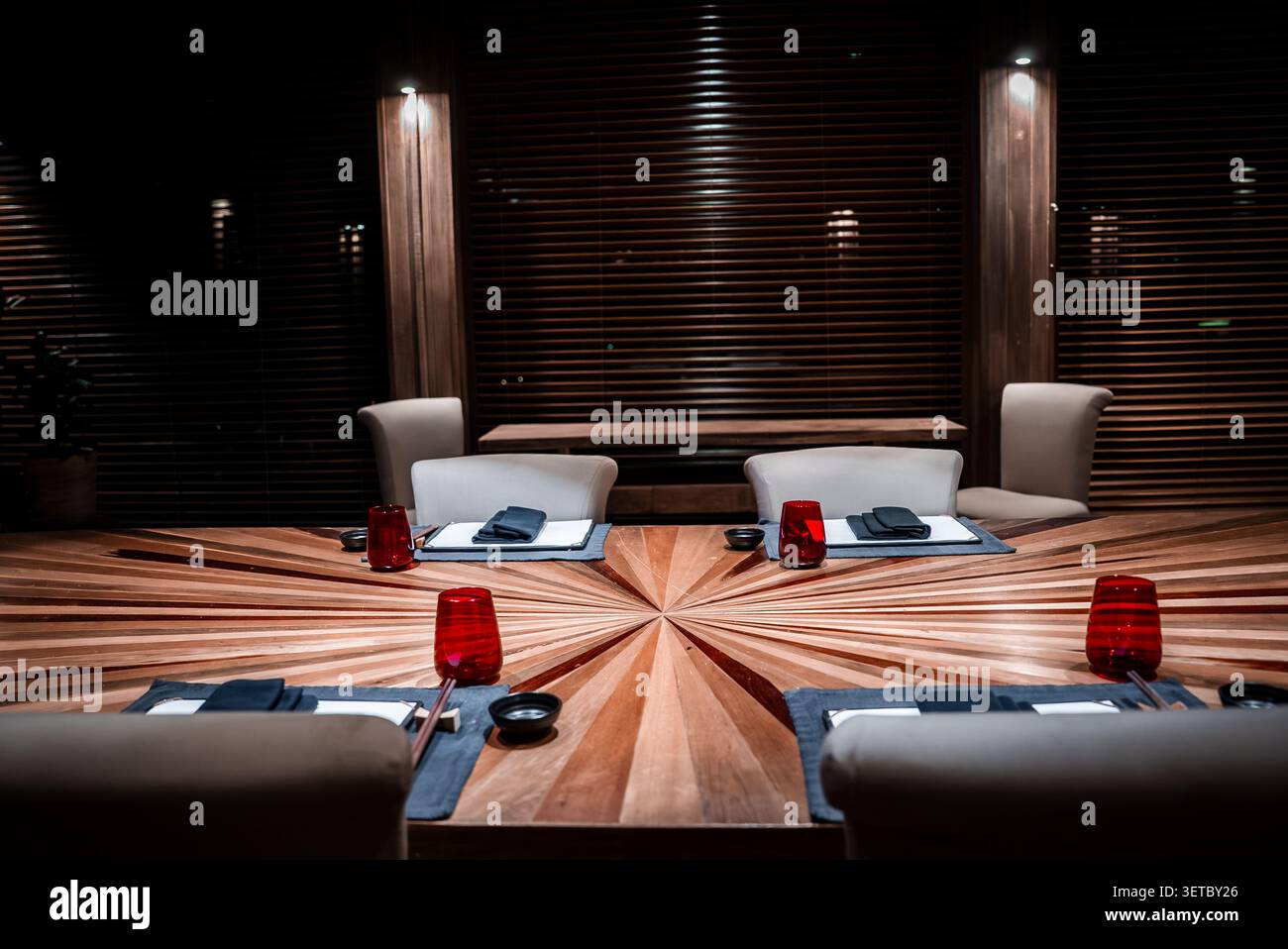 Lussuosa sala da pranzo con tavolo in legno radiale e bicchieri d'acqua rossi Foto Stock