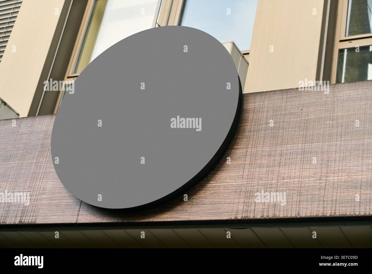 Per il modello di mockup di spazi pubblicitari, un cartello rotondo vuoto per la promozione del marchio e il design personalizzato, il cartello del negozio vuoto è montato su un edificio esterno pubblicità marketing aziendale. Foto Stock