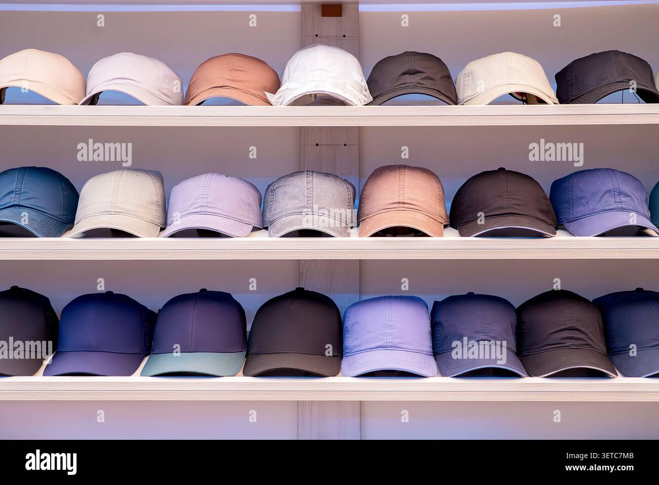 File di colorati berretti da baseball esposti ordinatamente sugli scaffali di un negozio di abbigliamento. Concetto: Moda di mercato di massa, varietà di copricapo e shopping Foto Stock