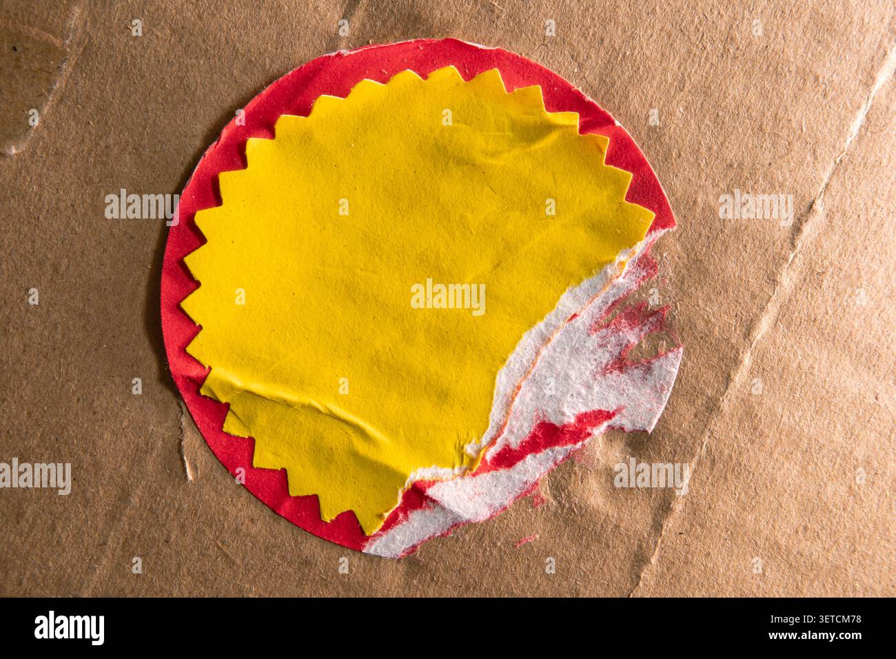 Elemento di design di mockup con una grafica a forma di stella gialla strappata in un adesivo sconto a cerchio rosso su una confezione di cartone invecchiato Foto Stock