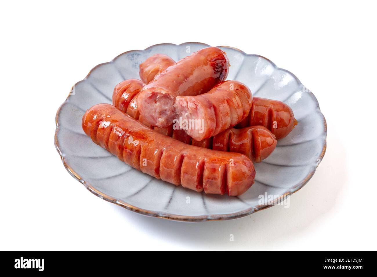Pila di salsicce di maiale grigliate senza additivi con tagli a spirale su un piatto di ceramica, una rotta per mostrare la consistenza, isolata su sfondo bianco Foto Stock