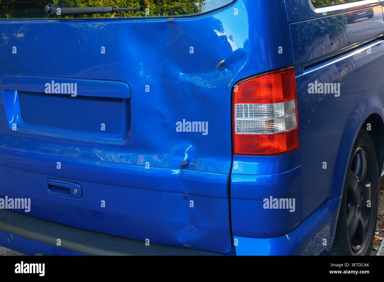 Furgone blu che mostra ammaccature e graffi significativi sulla carrozzeria posteriore vicino alle luci di posizione posteriori. Foto Stock