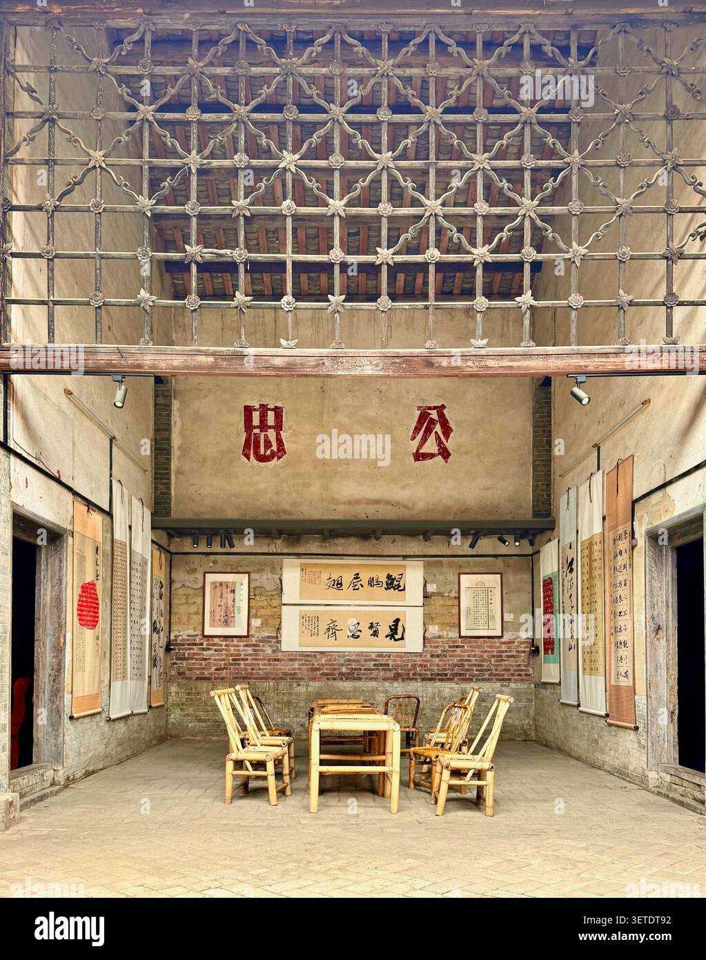 Interno di una sala cinese storica con schermo a grata in legno intarsiato, rotoli di calligrafia, mobili in bambù, villaggio tradizionale, Guangxi, Cina - Immagine stock catturata con smartphone