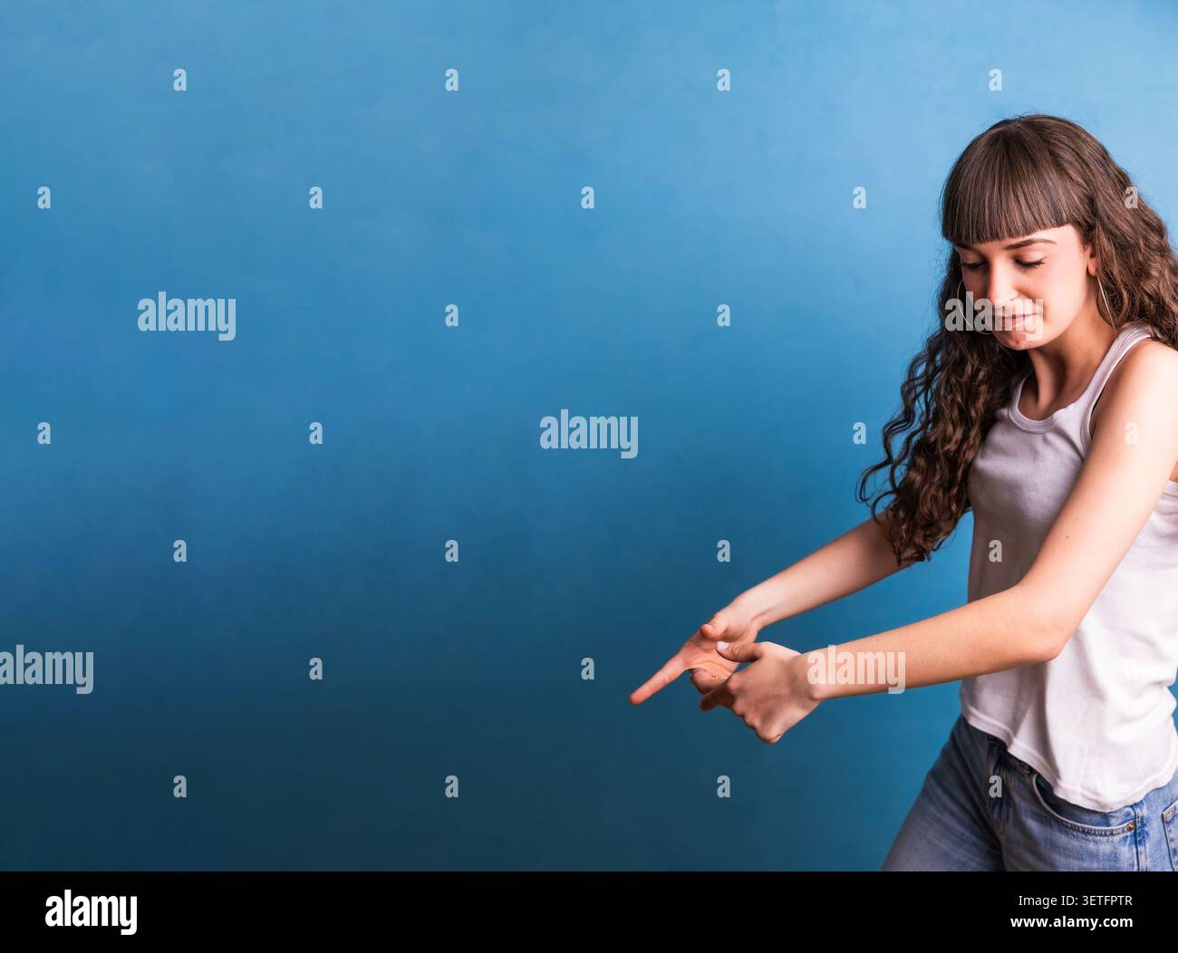 Giovane donna che punta le dita verso il basso su sfondo blu Foto Stock