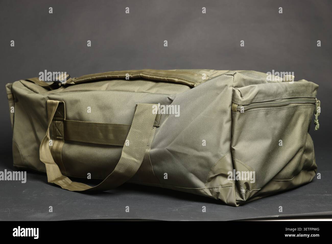 Borsa militare su sfondo grigio scuro. Attrezzature militari Foto Stock