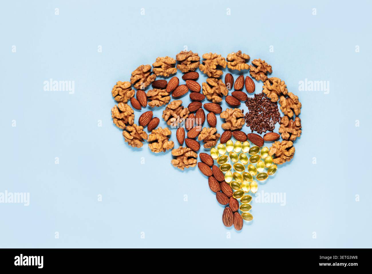Forma cerebrale umana formata da noci, mandorle, semi di lino, sfondo blu omega-3, che rappresenta alimenti intelligenti, nutrizione, funzione cognitiva Foto Stock