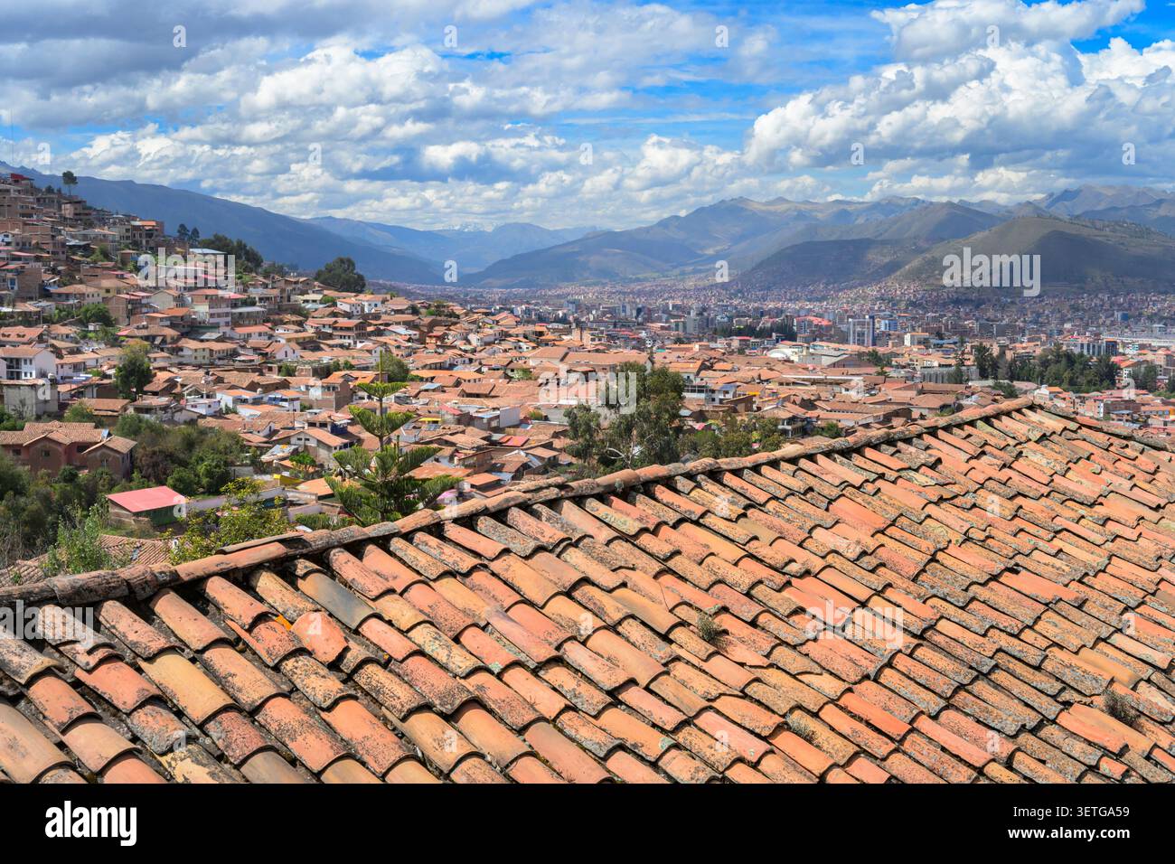 Vecchi tetti di terracotta e vista panoramica di Cusco, Perù, sulle pendici andine, con cielo blu e nuvole. Foto Stock