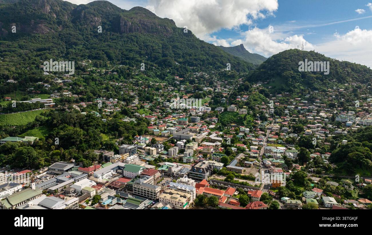 Una collina densamente popolata con case circondate da una lussureggiante vegetazione verde e ripidi pendii. Seychelles, Mahe. Victoria. Foto Stock