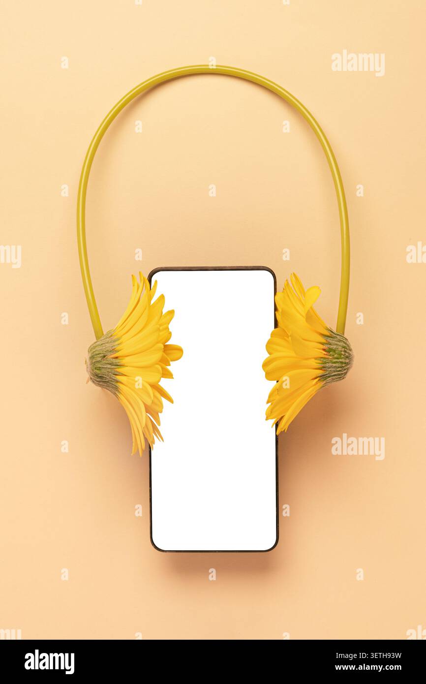 Composizione creativa di un mockup per smartphone con cuffie a fiori gialli su un morbido sfondo beige. Concetto di app musicale, podcast e audiolibri streamin Foto Stock
