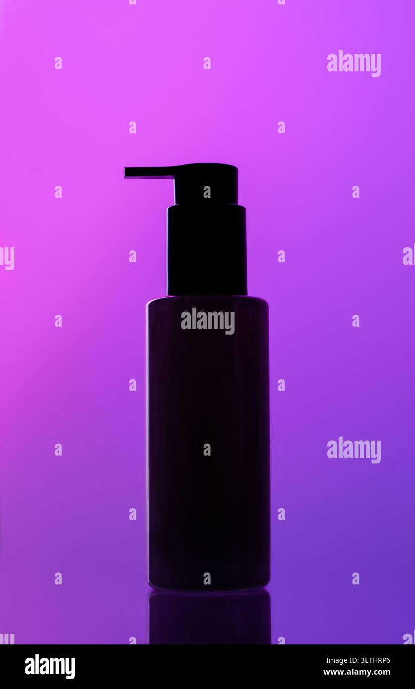 Silhouette scura del flacone con dispenser a pompa su sfondo gradiente viola-viola brillante, superficie riflettente sottile Foto Stock