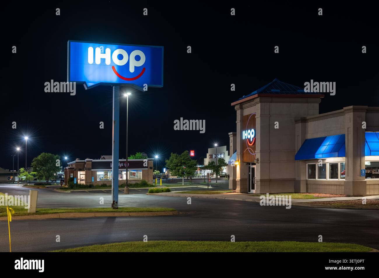 WAITE PARK, MINNESOTA, Stati Uniti - 19 giugno 2026: Di notte viene mostrato un ristorante IHOP con un grande cartello illuminato sul lato della strada e accenti esterni illuminati di blu. Foto Stock