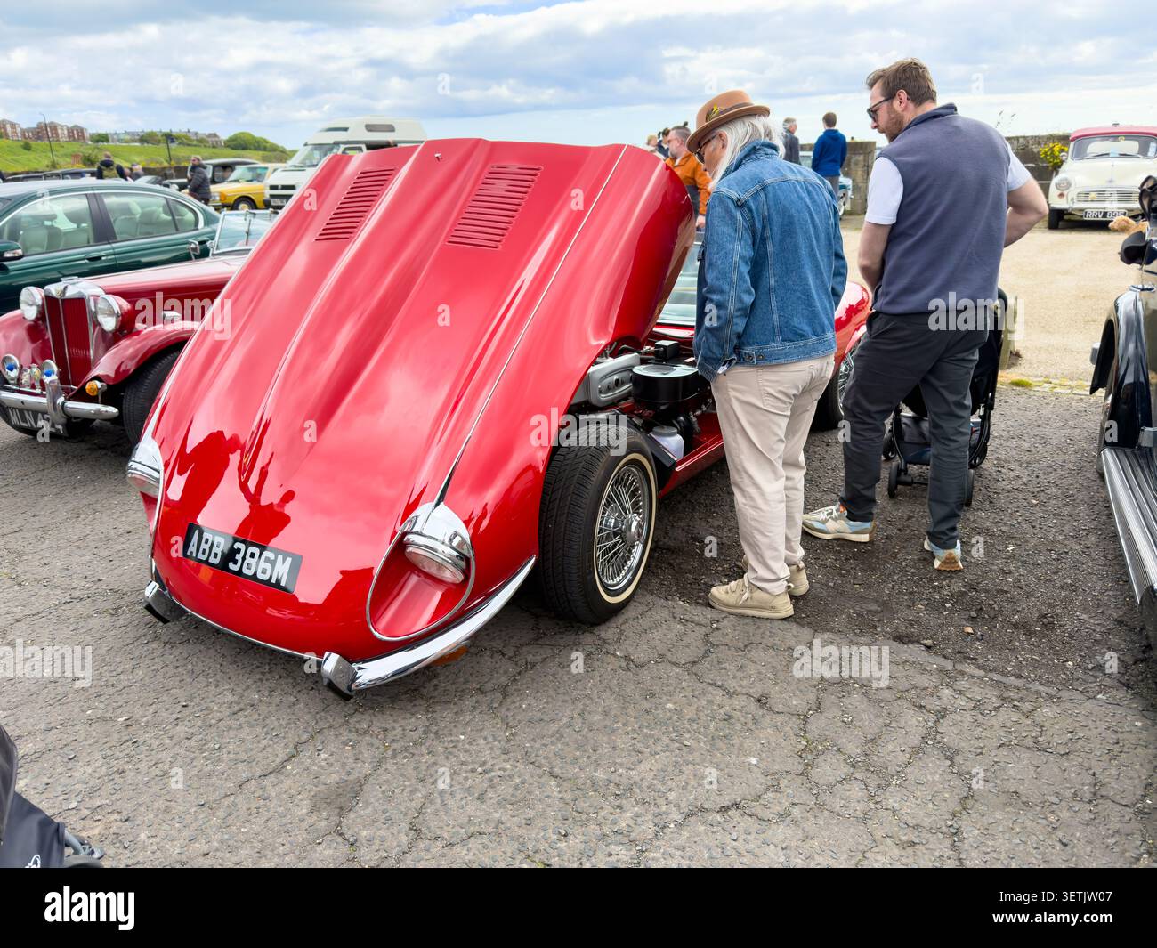 Classica jaguar e-TYPE rossa in mostra a un salone di auto all'aperto in Inghilterra con persone che guardano all'interno - Immagine stock catturata con smartphone