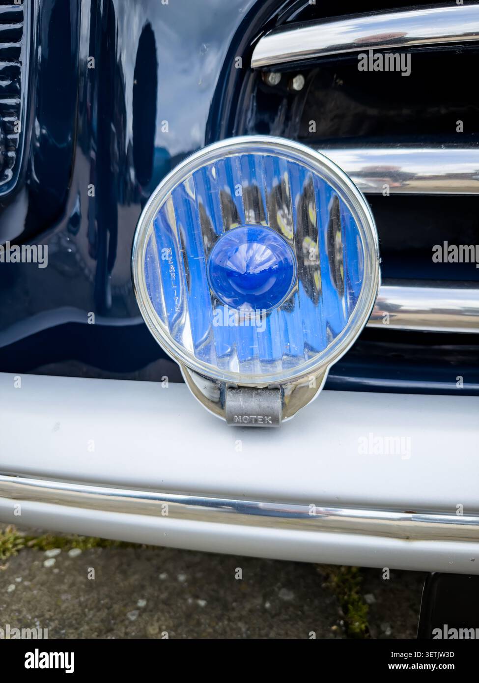 Primo piano di un faretto blu Notex Nearlite su un'auto d'epoca britannica con dettagli cromati e vernice blu Foto Stock