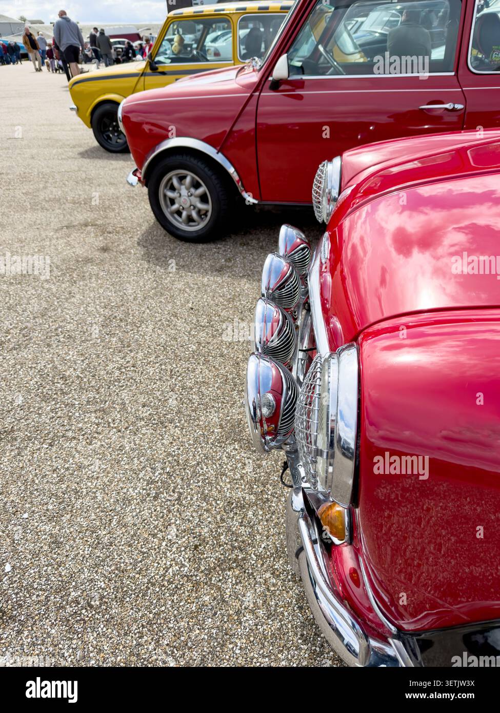 Le classiche Mini Cooper rosse e gialle sono parcheggiate di fila in una mostra di auto all'aperto - Immagine stock catturata con smartphone