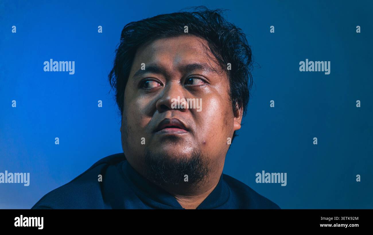 Un personaggio maschile ansioso guarda indietro sulla sua spalla con gli occhi larghi, rivelando una forte sensazione di paranoia, paura profonda e shock improvviso. Gocciolamento di sudore Foto Stock